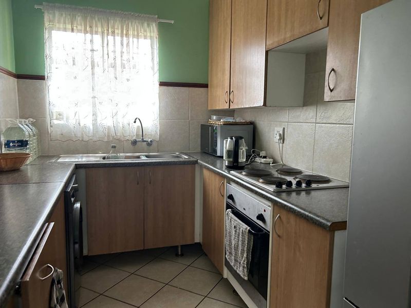 A functional kitchen featuring laminate cabinetry, tiled backsplash, built-in oven, and electric hob, offering a practical layout with ample storage space.