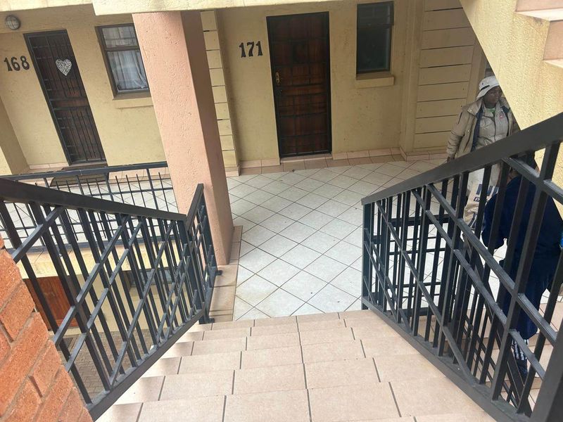 Exterior view of an apartment building entrance featuring a tiled staircase, metal security railings, and access doors to units 168 and 171.