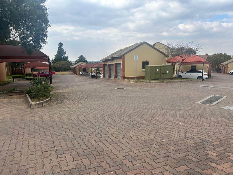 Exterior view of the apartment complex parking area featuring paved driveways, multiple garage units, and covered carport structures.