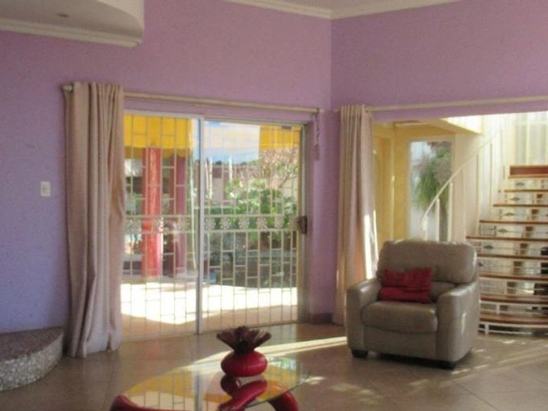 Spacious living room featuring a built-in fireplace, tiled flooring, and a spiral staircase, with sliding glass doors providing access to the outdoor area.