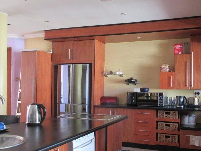 A functional kitchen featuring wood-finish cabinetry, a central island with an integrated sink, and ample counter space for meal preparation.