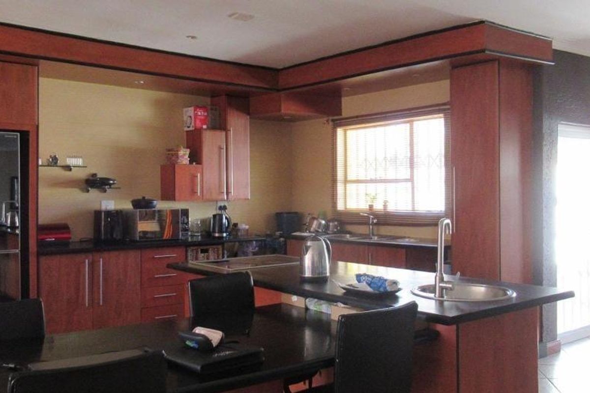 A functional kitchen featuring dark wood cabinetry, granite countertops, a central island with a secondary sink, and recessed lighting.