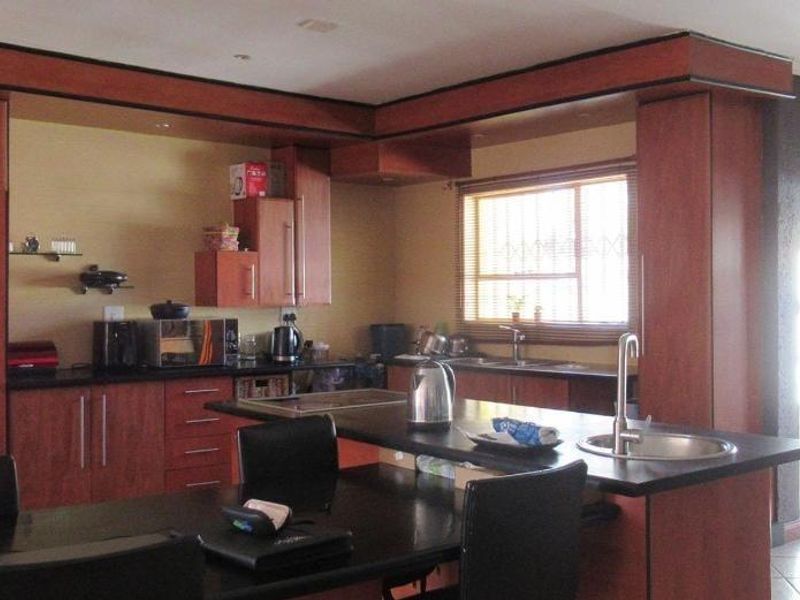 A functional kitchen featuring dark wood cabinetry, granite countertops, a central island with a secondary sink, and recessed lighting.