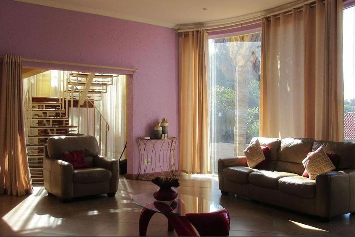 Spacious living area featuring large floor-to-ceiling windows, tiled flooring, and an integrated spiral staircase leading to the upper level.
