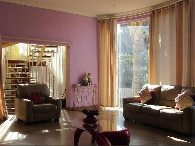 Spacious living area featuring large floor-to-ceiling windows, tiled flooring, and an integrated spiral staircase leading to the upper level.