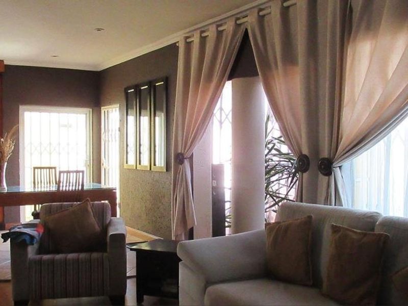 An open-plan living and dining area featuring a combination of tiled and laminate flooring, recessed lighting, and direct access to the exterior.