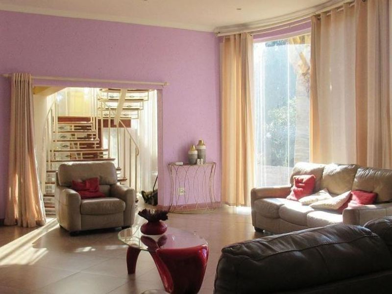 Spacious living room featuring large floor-to-ceiling windows, tiled flooring, and an open transition to a spiral staircase area.