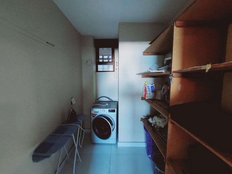 A functional laundry area featuring tiled flooring, built-in wooden shelving, and a dedicated space for a washing machine.