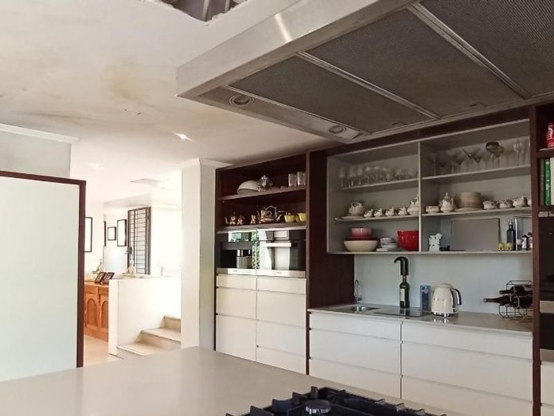 Modern kitchen featuring built-in appliances, extensive cabinetry, and a central island, currently showing signs of ceiling water damage requiring repair.