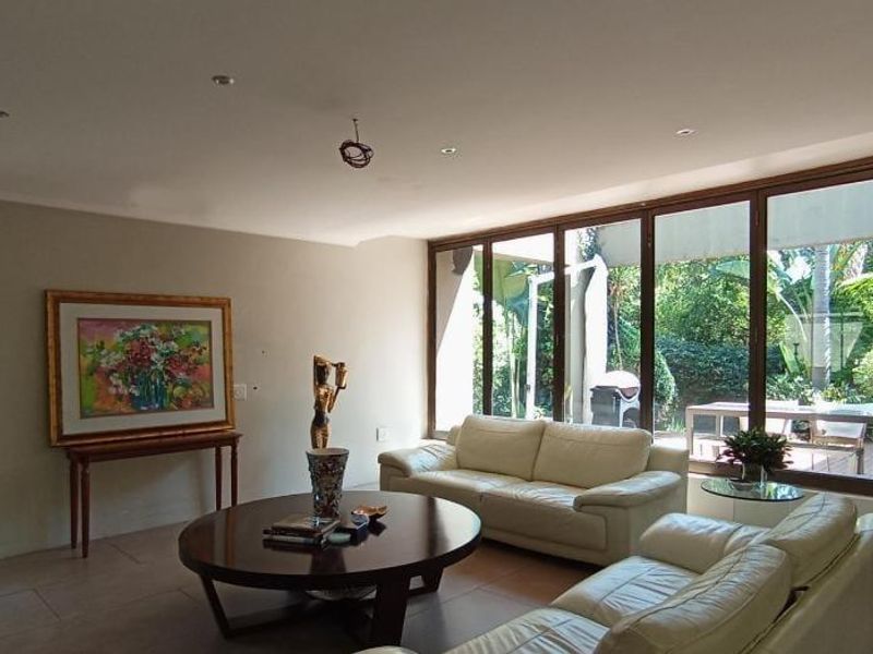Spacious living room featuring large glass sliding doors that provide ample natural light and direct access to the garden area.
