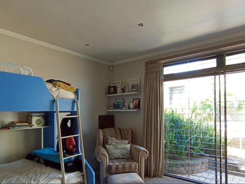 A bedroom featuring recessed lighting and a large sliding glass door with security bars, providing direct access to the outdoor area.