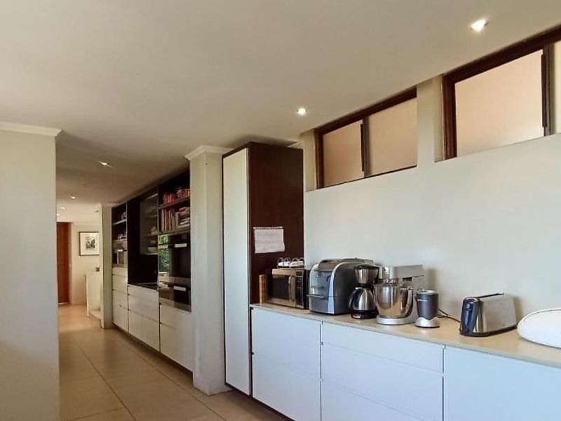 Modern kitchen featuring sleek built-in cabinetry, stone countertops, integrated appliances, and high-level clerestory windows providing natural light.