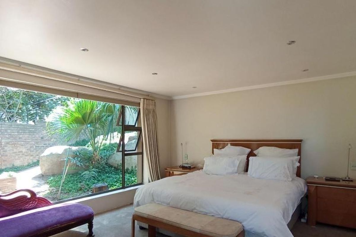 Spacious bedroom featuring a large picture window with garden views, recessed downlighting, and neutral wall finishes.