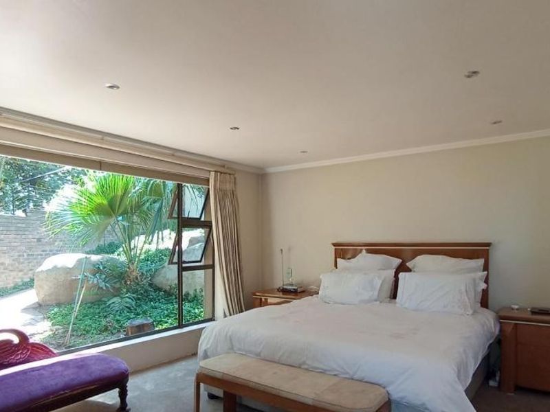 Spacious bedroom featuring a large picture window with garden views, recessed downlighting, and neutral wall finishes.
