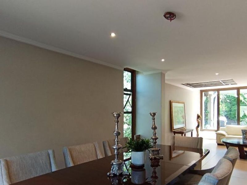 Spacious open-plan living and dining area featuring tiled flooring, recessed downlighting, and large glass doors providing natural light and garden access.