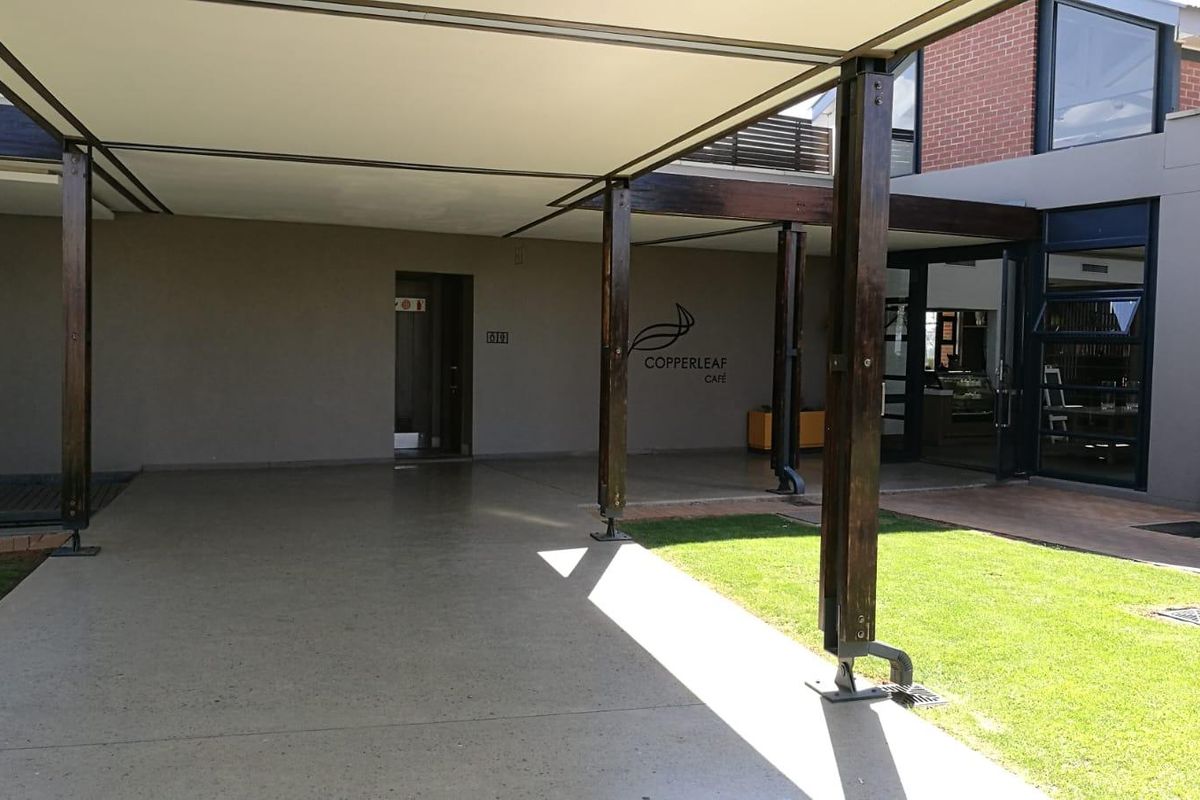 A spacious covered patio area featuring timber support columns, concrete flooring, and direct access to the building interior.