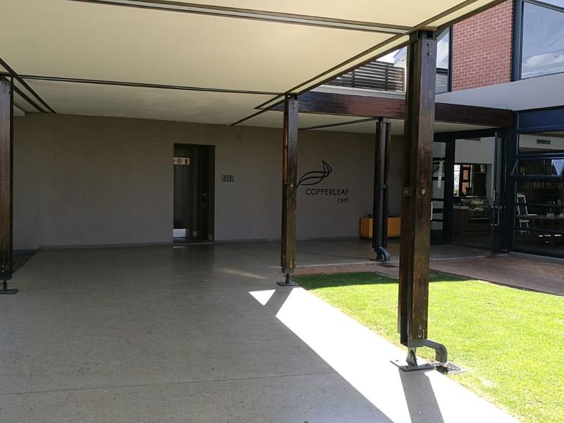 A spacious covered patio area featuring timber support columns, concrete flooring, and direct access to the building interior.