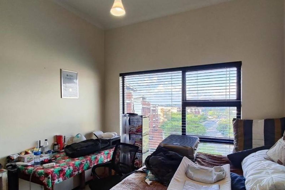 A bedroom featuring a large window with venetian blinds, providing natural light and an exterior view.