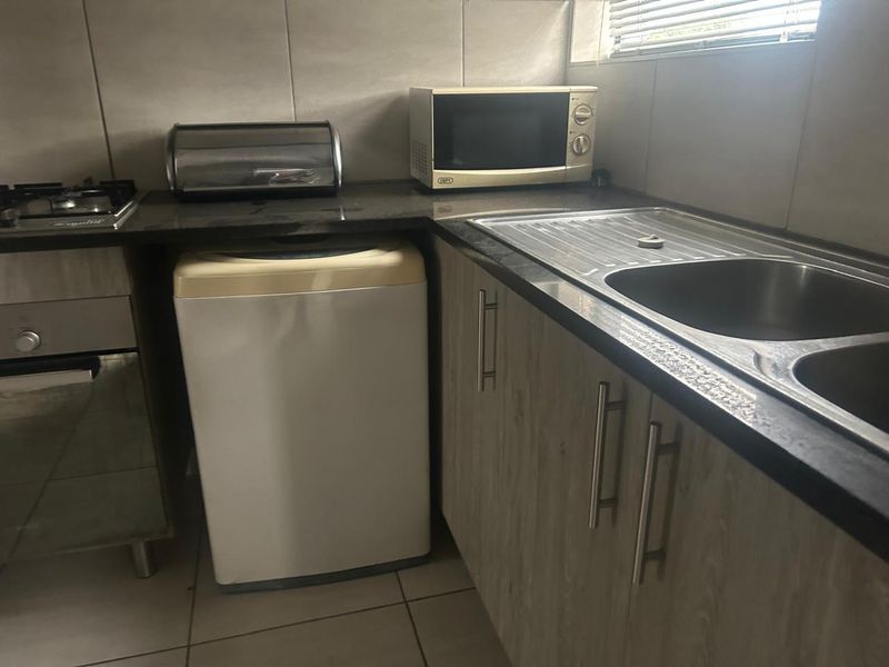 A functional kitchen featuring laminate cabinetry, granite countertops, a stainless steel sink, and a built-in oven with a gas hob.