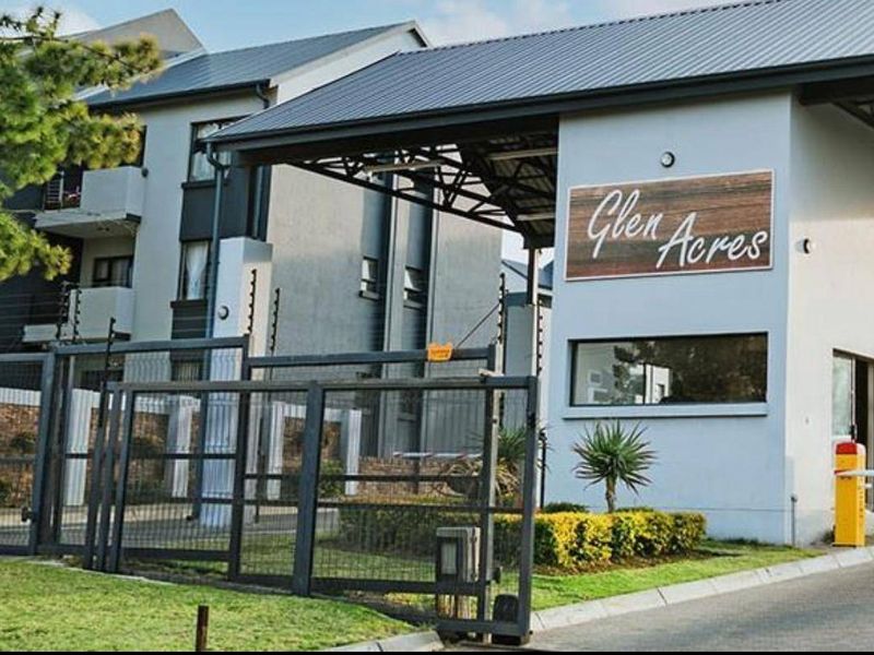 The secure entrance to Glen Acres apartment complex, featuring a guard house, automated boom gate, and perimeter security fencing.