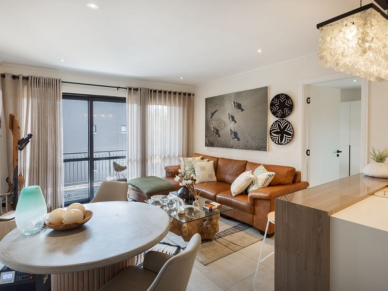 A bright open-plan living and dining area featuring tiled floors, recessed lighting, and direct access to a private balcony through sliding glass doors.