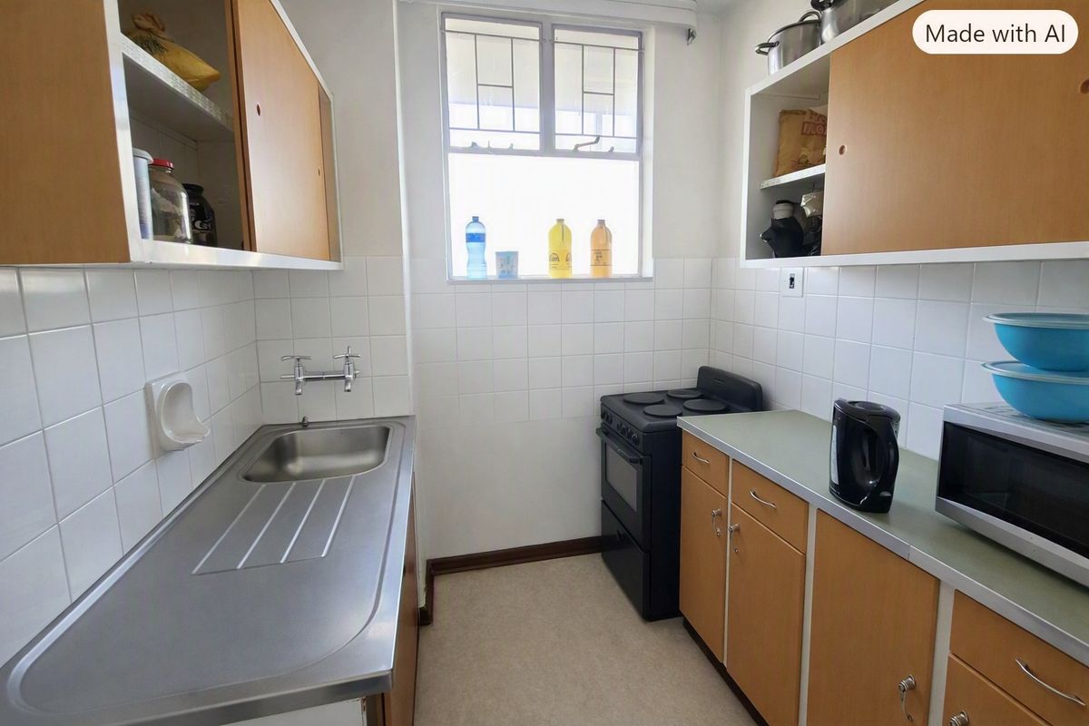 A compact, functional kitchen featuring dated wooden cabinetry, a stainless steel sink, tiled splashbacks, and a freestanding stove.