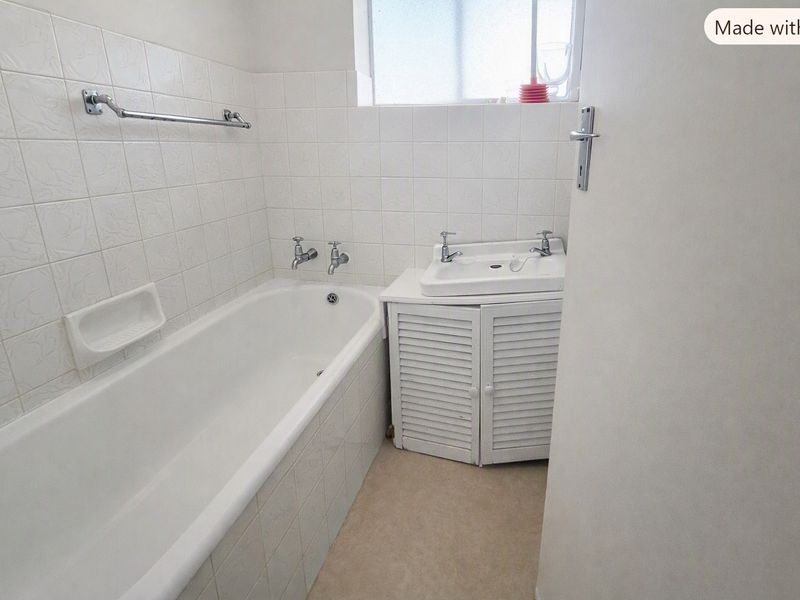 A compact bathroom featuring a built-in bathtub, a vanity cabinet with a basin, and tiled wall finishes.