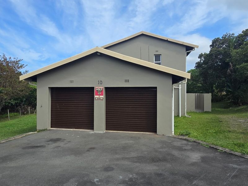 A detached double garage with a pitched roof and asphalt driveway, situated in a landscaped residential setting.