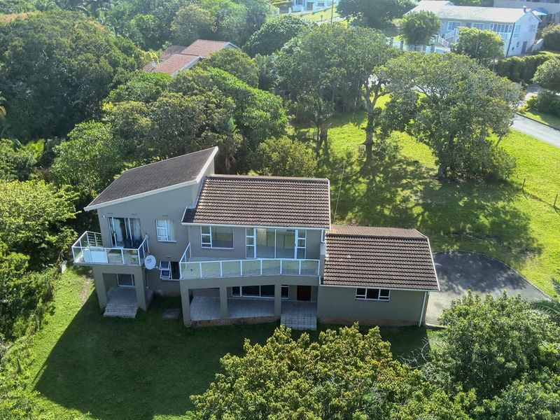 Aerial view of a multi-level residential property featuring a tiled roof, upper-level balconies with glass balustrades, and a spacious garden setting.