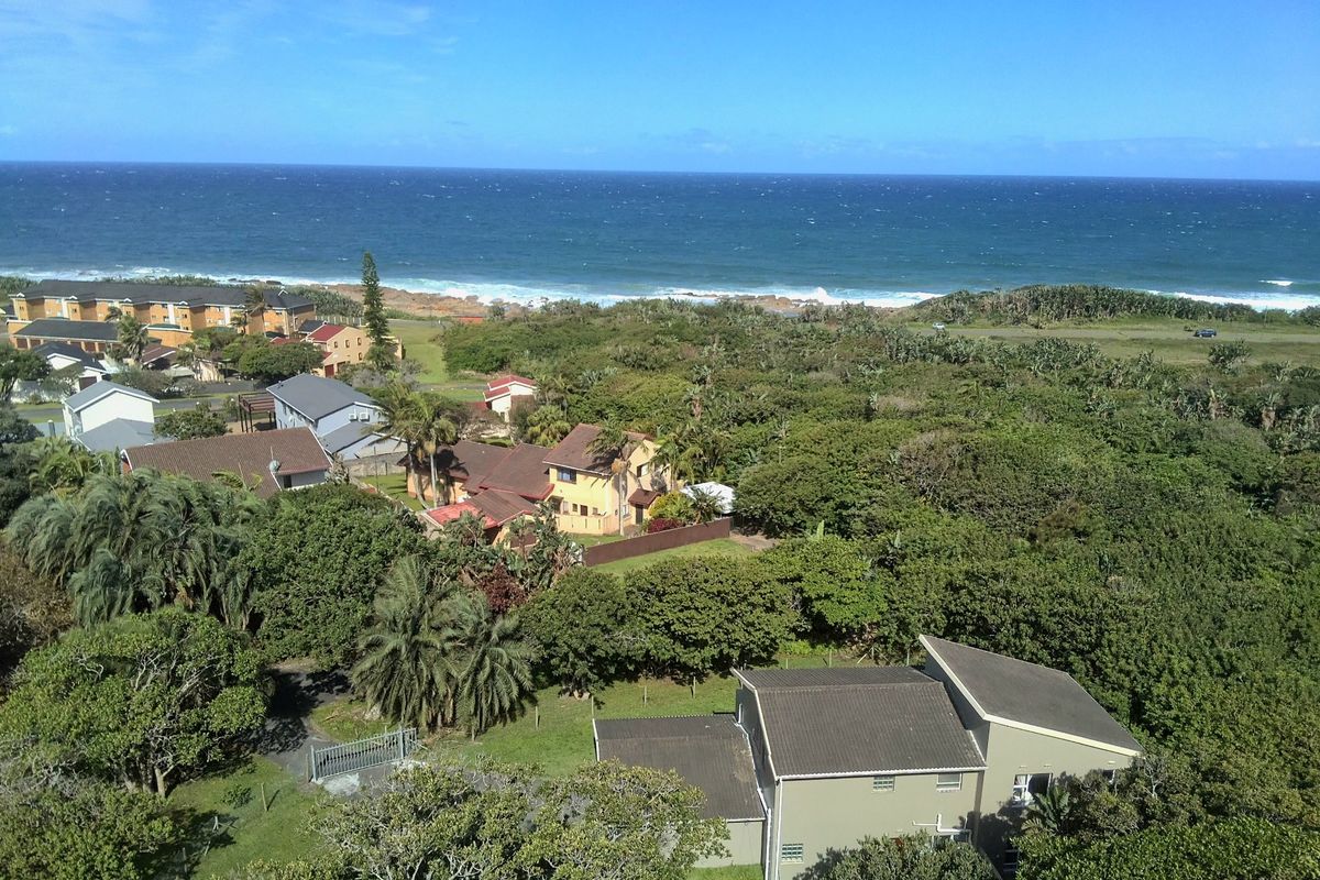 An aerial view of the coastal residential property, showcasing the surrounding neighborhood, lush vegetation, and proximity to the ocean.