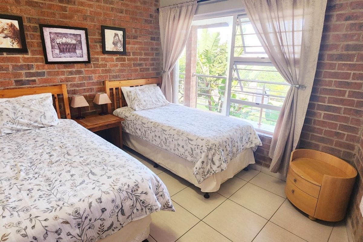 A bedroom featuring exposed brick walls, tiled flooring, and a sliding glass door providing access to an outdoor area.