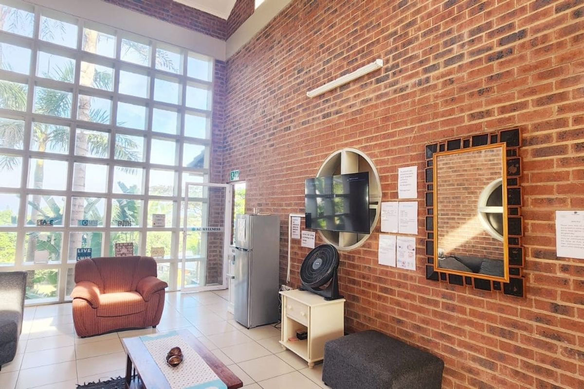 Spacious living area featuring high vaulted ceilings, exposed brick walls, and expansive floor-to-ceiling windows that provide abundant natural light.