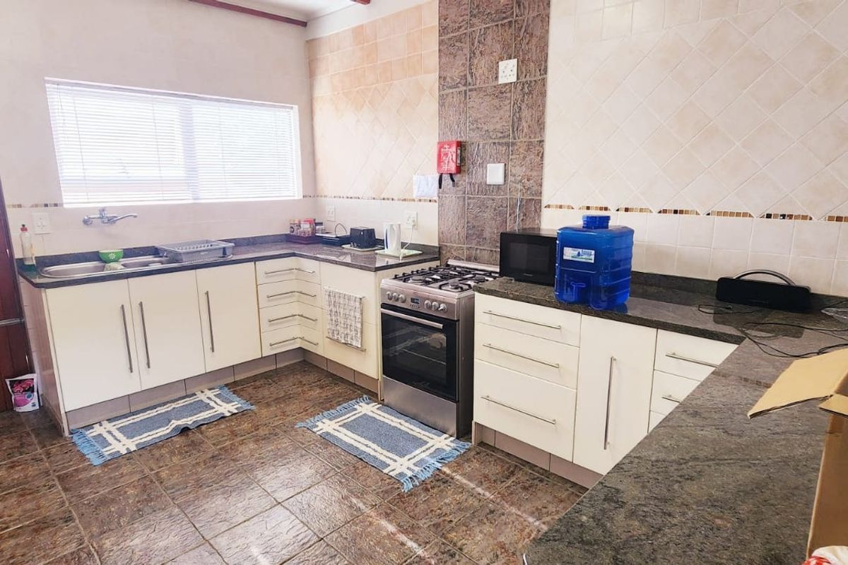 Functional kitchen featuring granite countertops, built-in cabinetry, a stainless steel gas stove, and tiled backsplash, providing a practical workspace for commercial use.