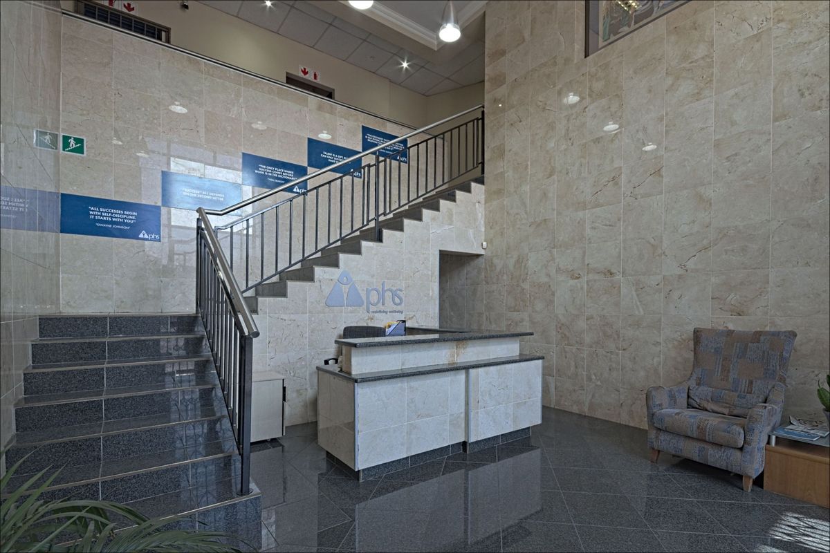 Professional commercial lobby featuring polished marble wall cladding, a granite staircase with metal railings, and a custom-built reception desk.