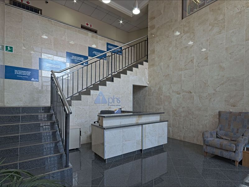 Professional commercial lobby featuring polished marble wall cladding, a granite staircase with metal railings, and a custom-built reception desk.