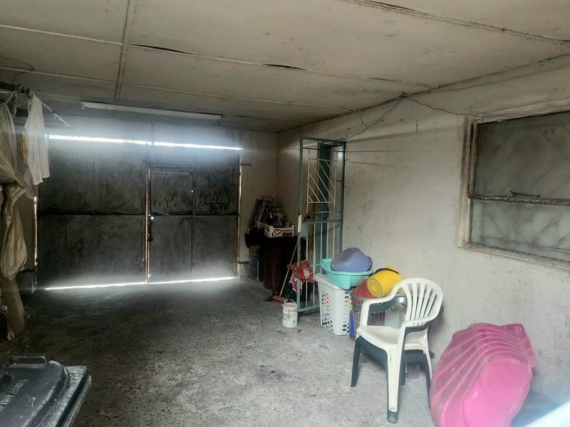 A functional garage space featuring concrete flooring, a metal door, and a side window, currently requiring maintenance and cosmetic updates.