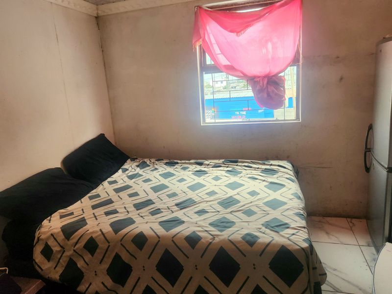 A bedroom featuring tiled flooring and a window with security bars, requiring cosmetic updates to the wall finishes.