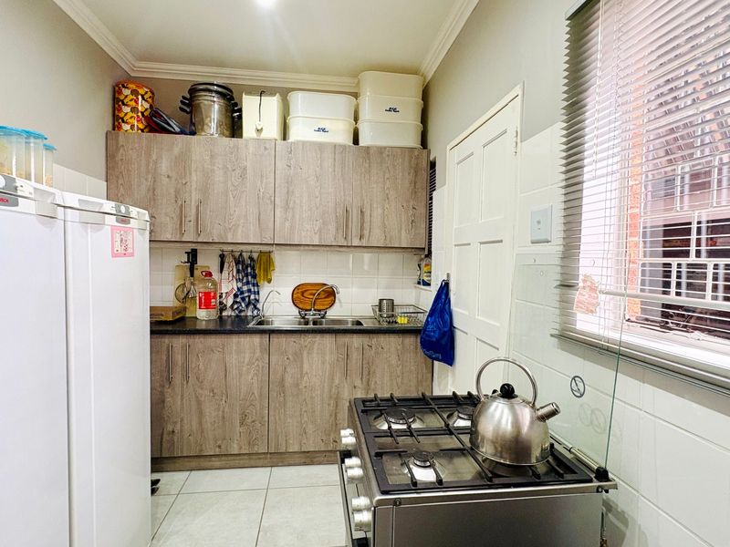A functional scullery featuring laminate cabinetry, a stainless steel sink, tiled backsplash, and a gas hob, providing additional prep and wash-up space.