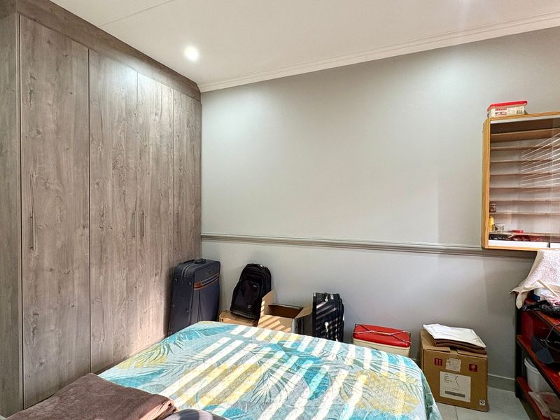 A bedroom featuring a large built-in wardrobe with wood-grain finish, decorative dado rail, and coving detail.