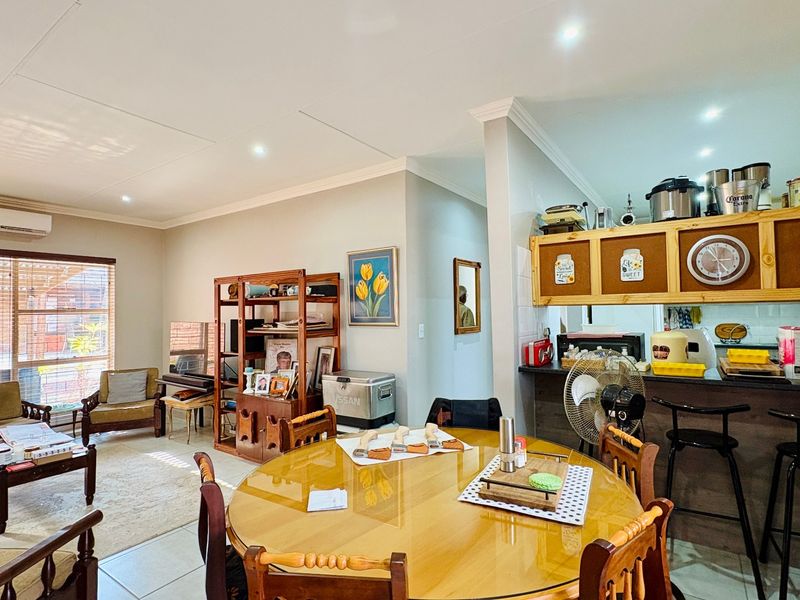 Open-plan living and dining area featuring tiled floors, recessed lighting, a split-system air conditioner, and a functional kitchen breakfast bar.