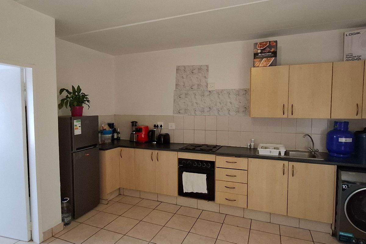 Functional kitchen featuring light wood cabinetry, laminate countertops, built-in oven with gas hob, and tiled flooring with a tiled backsplash area.