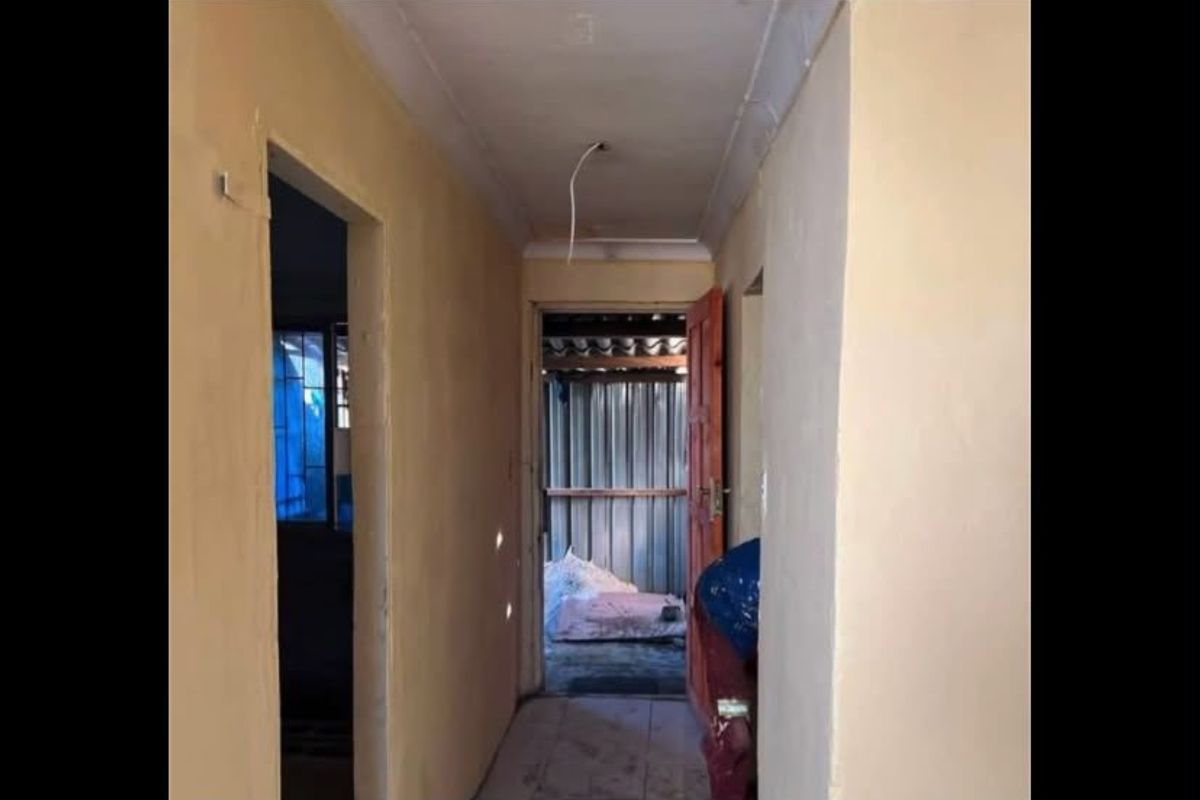 A narrow hallway showing signs of wear with exposed electrical wiring and unfinished wall surfaces, requiring cosmetic updates and repairs.