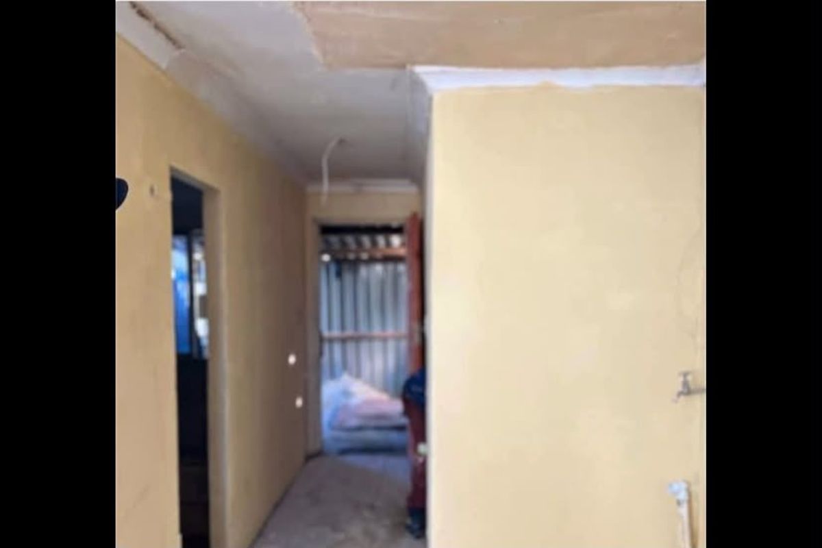 A narrow hallway area in a state of renovation, featuring unfinished wall surfaces and exposed electrical wiring.