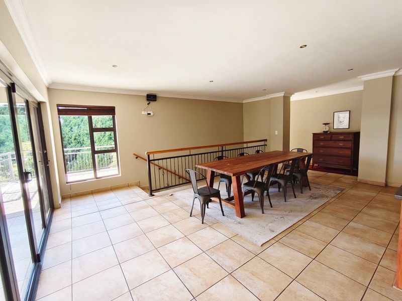 Spacious dining area featuring neutral tiled flooring, recessed lighting, and large sliding glass doors leading to an outdoor balcony with a metal balustrade.