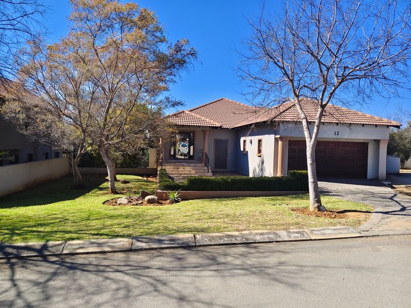 A well-maintained single-story residential property featuring a tiled roof, double garage, paved driveway, and a neat front garden.