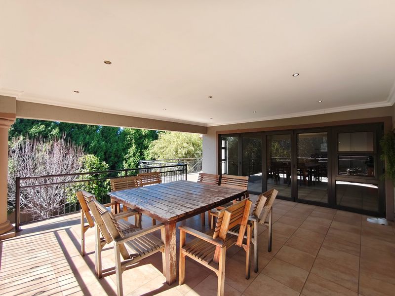 A spacious covered patio featuring tiled flooring, recessed downlighting, and a metal balustrade, providing a seamless transition to the outdoor area.