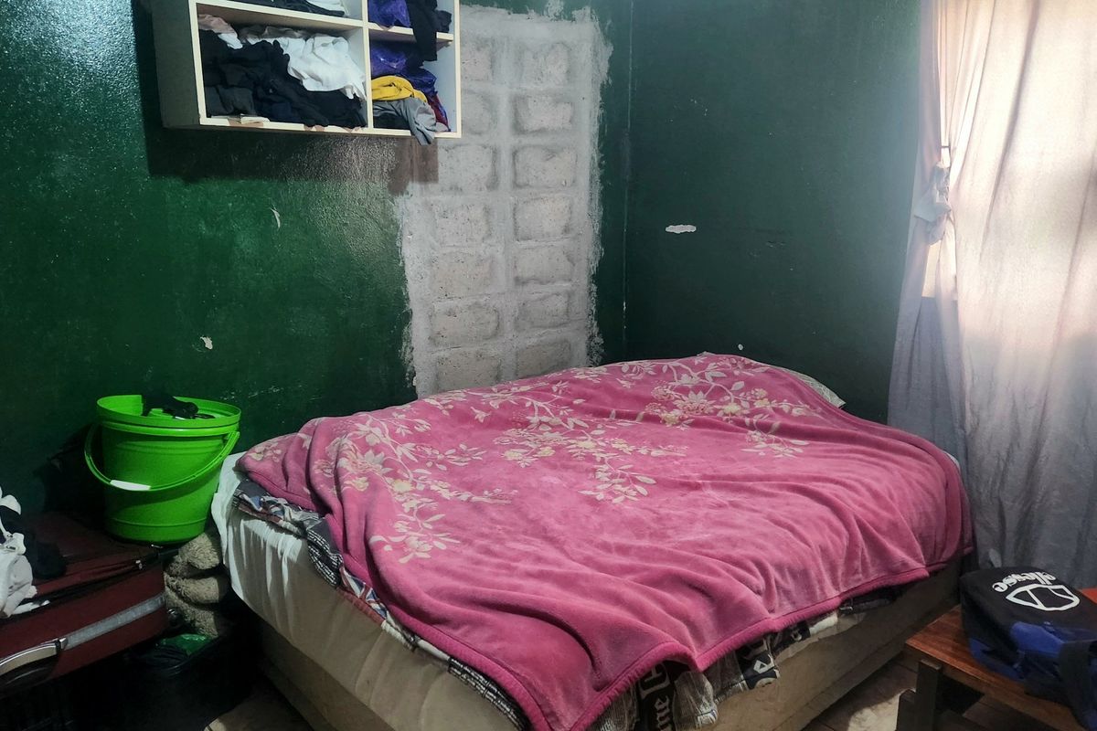 A bedroom featuring tiled flooring and a wall-mounted storage unit, currently requiring cosmetic repairs to the wall surfaces.