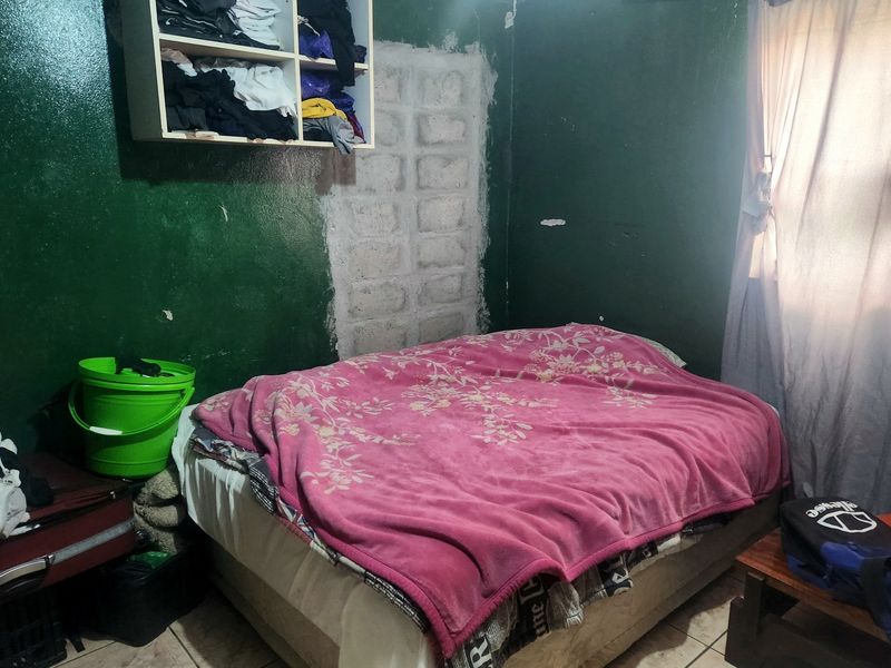 A bedroom featuring tiled flooring and a wall-mounted storage unit, currently requiring cosmetic repairs to the wall surfaces.