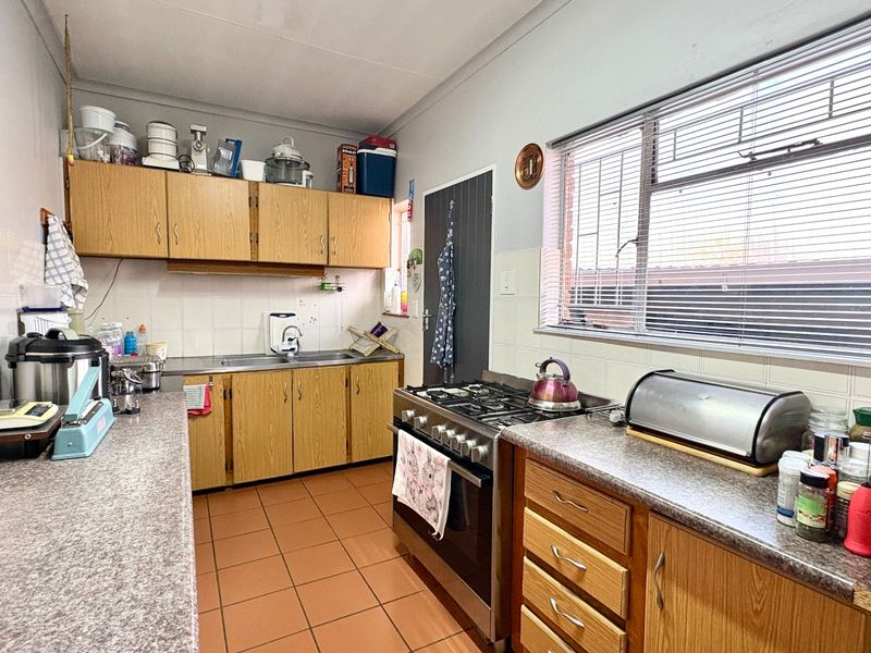A functional kitchen featuring laminate cabinetry, tiled backsplash, tiled flooring, and a stainless steel gas stove with oven.
