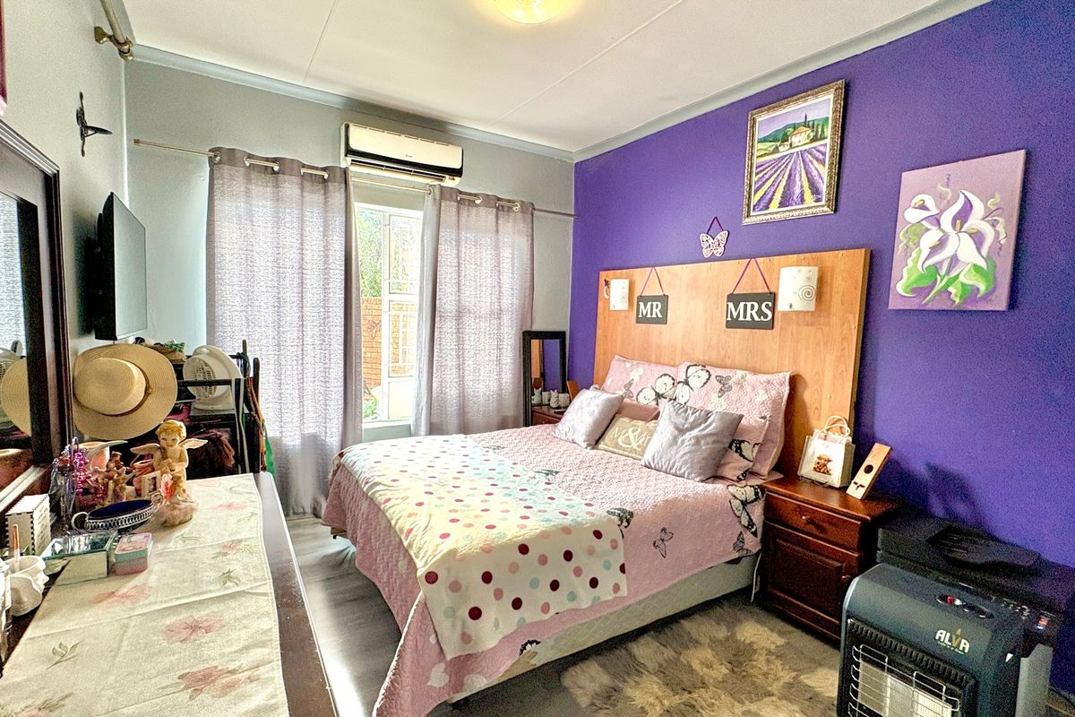 A bedroom featuring a built-in headboard and a wall-mounted split-system air conditioning unit.